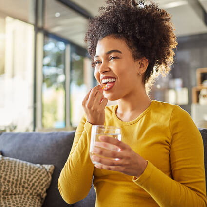 Woman taking supplement with water