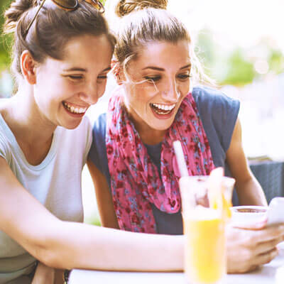 women eating laughing at phone