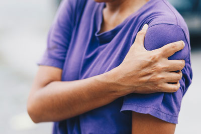 young adult holding shoulder in pain