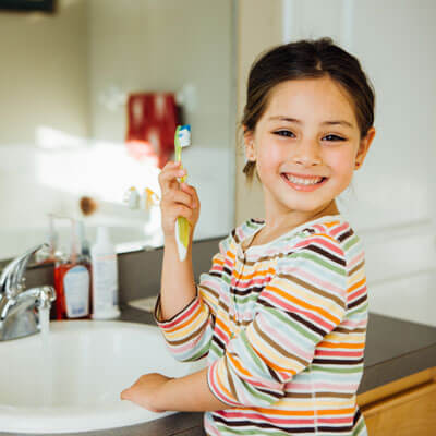 Young girl cleaning teeth at sink