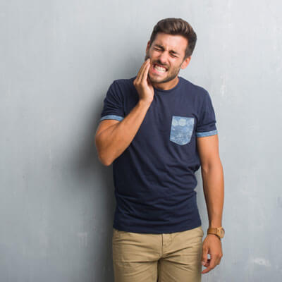 Man standing against wall with tooth pain