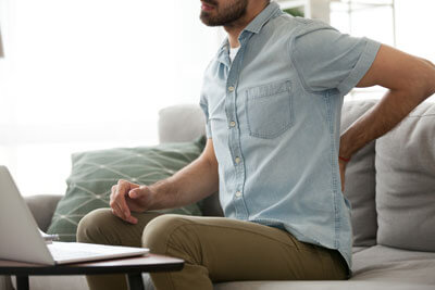 young man on couch with back pain