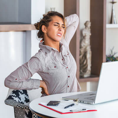 Young woman at computer with back and neck pain
