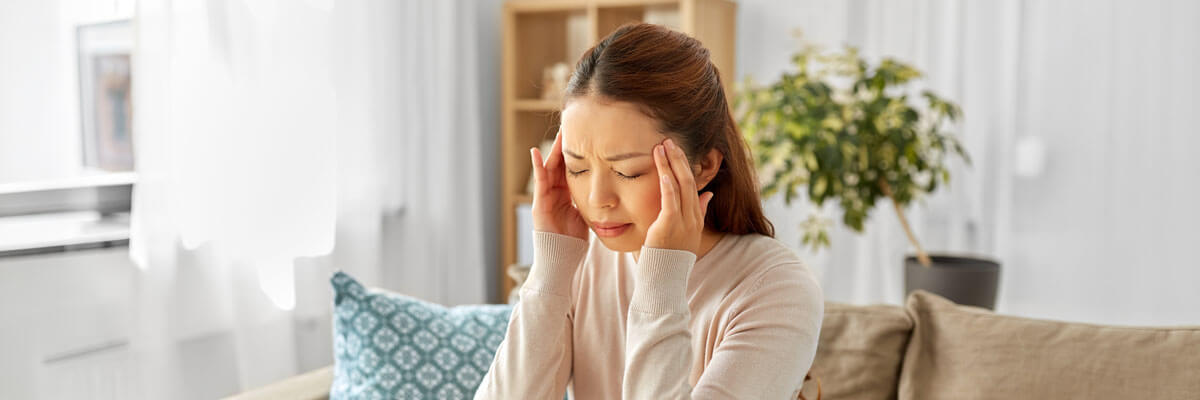 Young woman at home touching her temples with severe headache pain