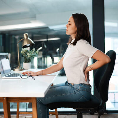 person with back pain at desk