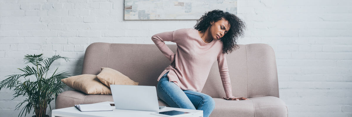woman sitting on couch in pain