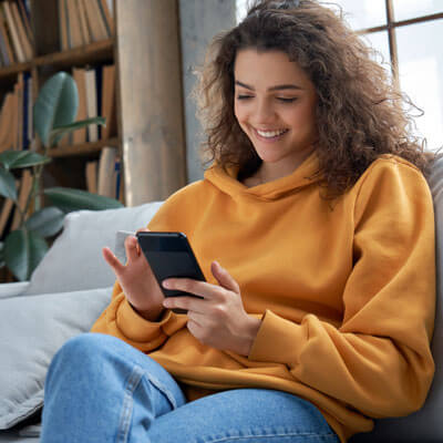 young woman on couch using phone