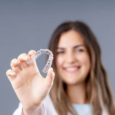 Girl holding out clear aligners tray