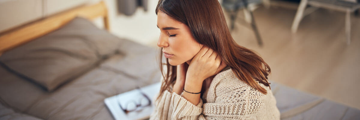 woman with hands on her neck in pain