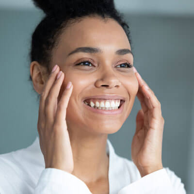 woman smiling and touching her cheeks