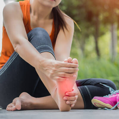 woman with foot pain sitting on floor